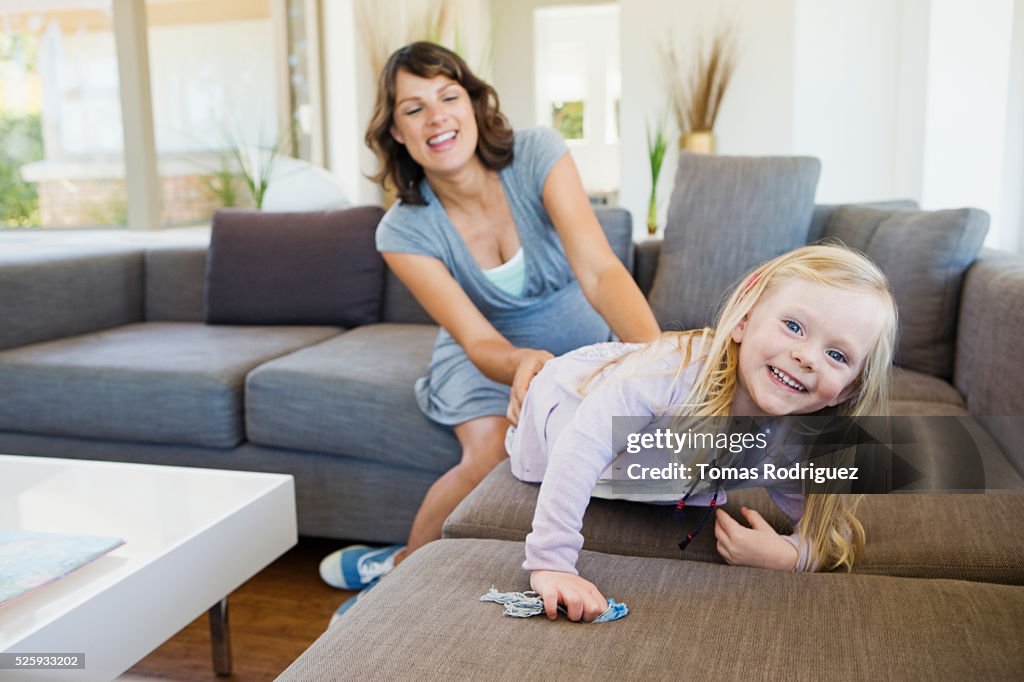 Pregnant woman and girl (2-3) playing in living room