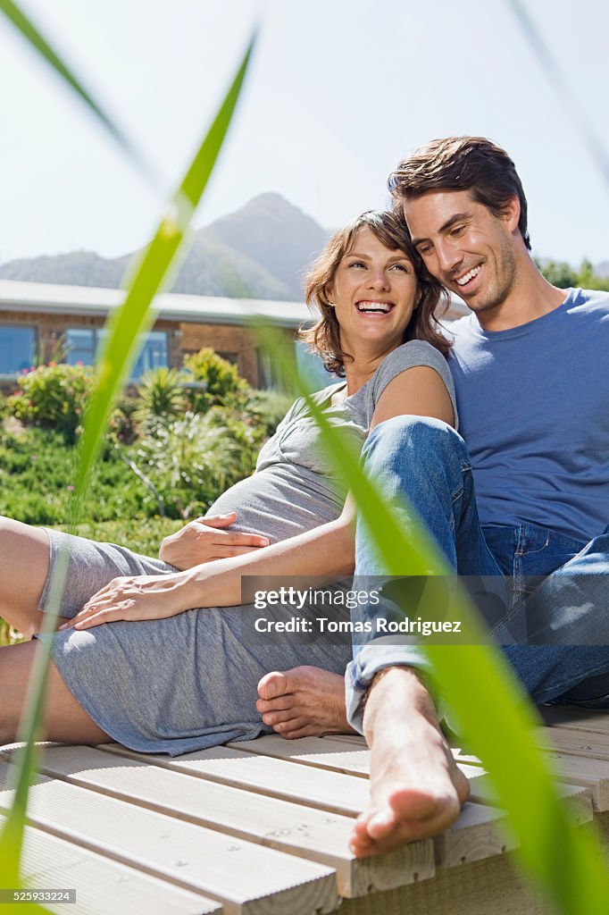 Man and pregnant woman sitting on jetty