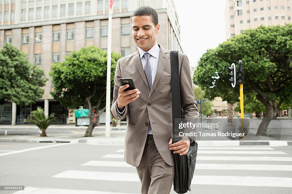 Mid adult man text messaging while crossing street