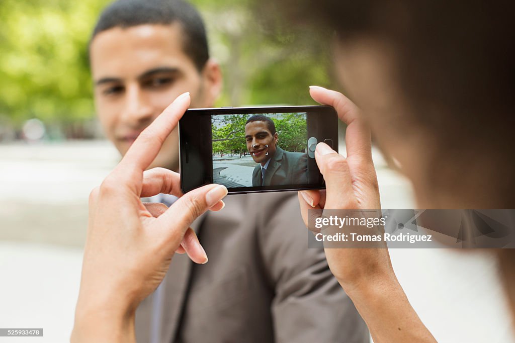 Woman taking photo of man with cell phone