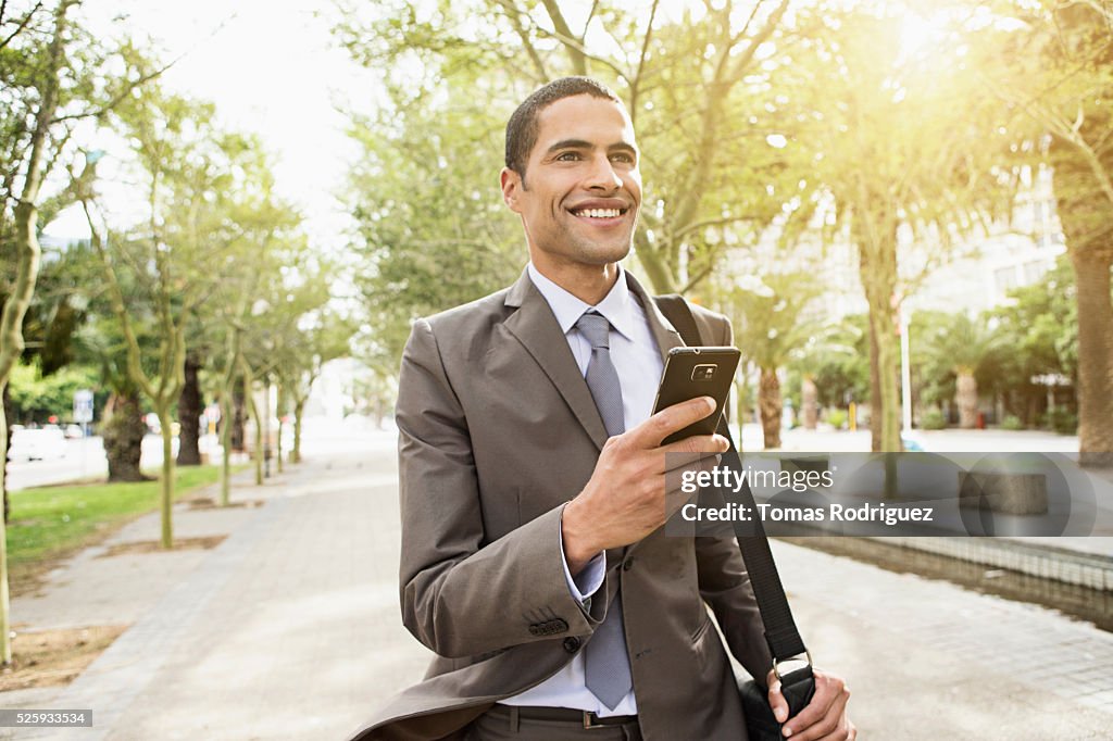Mid adult man text messaging while walking along pavement