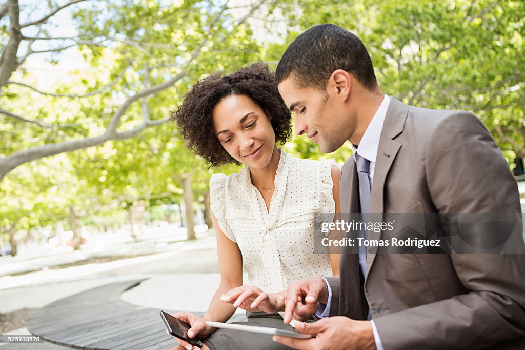 Man showing digital tablet to woman