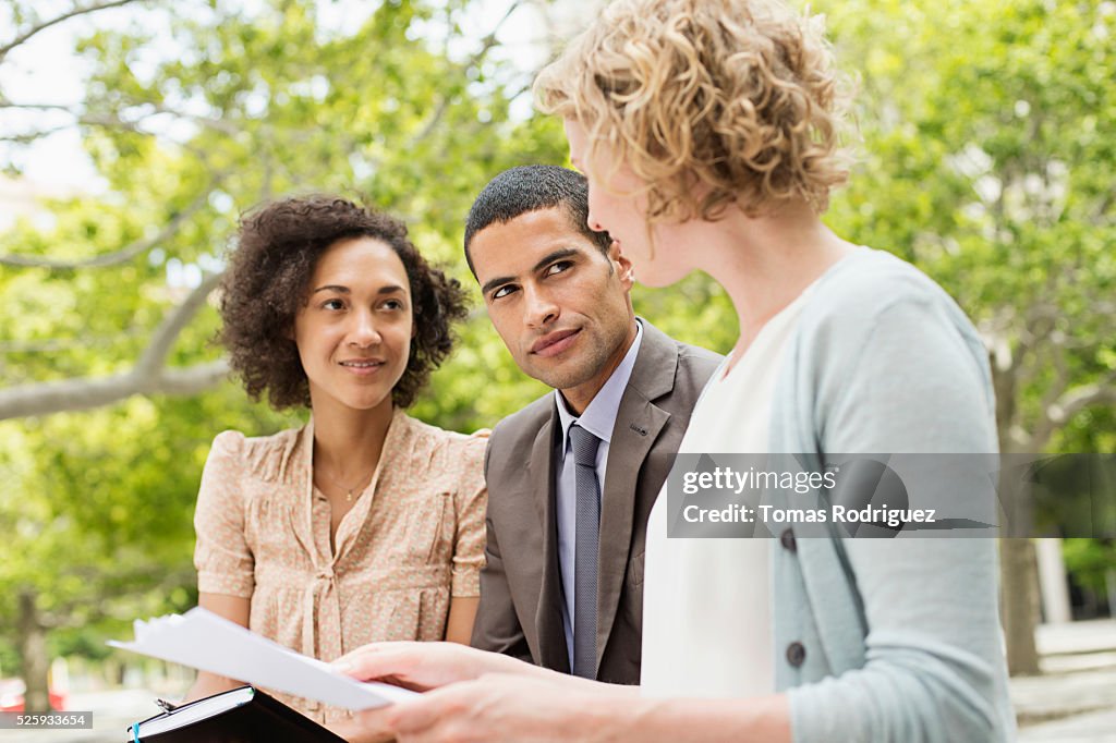 Mid adult women and men discussing in park