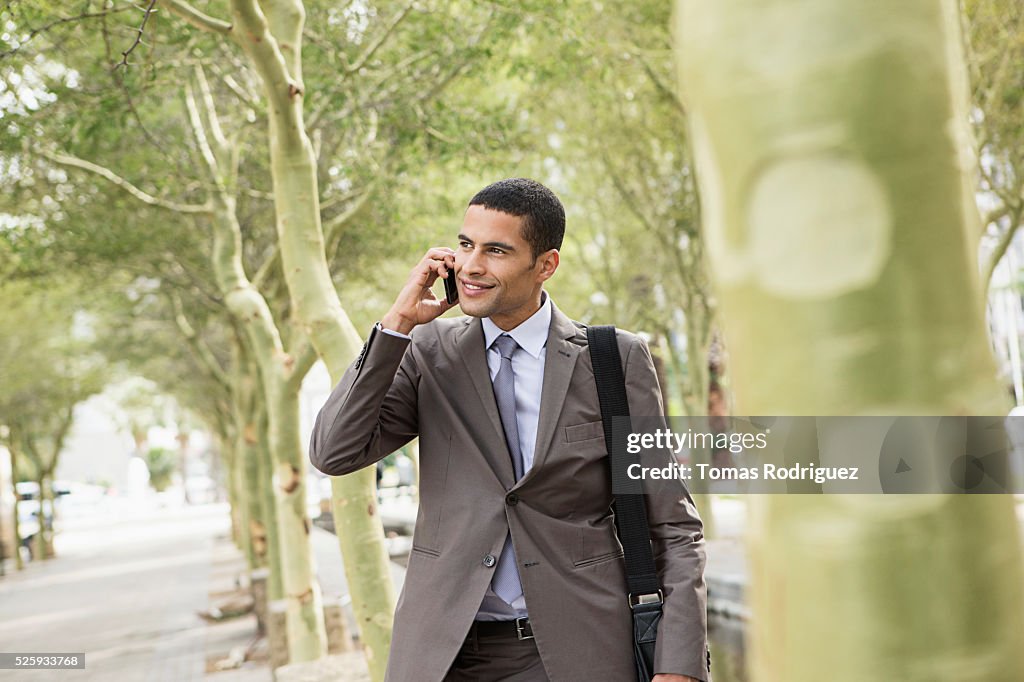 Mid adult man standing on pavement and talking on cell phone