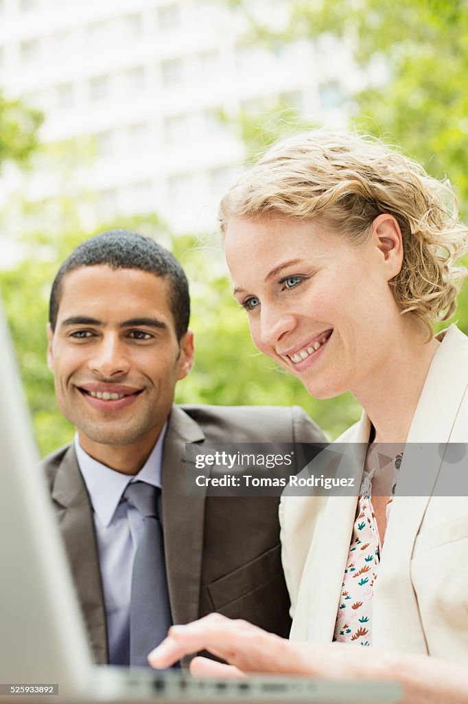 Portrait of mid adult man and woman working on laptop outdoor