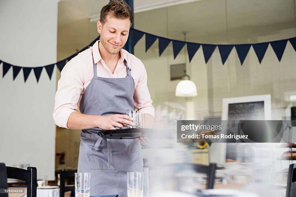 Portrait of mid adult waiter holding tray