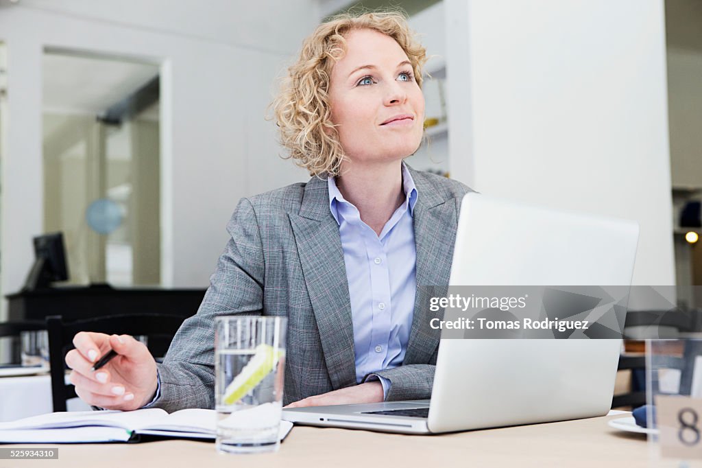 Portrait of mid adult woman with laptop sitting at restaurant table