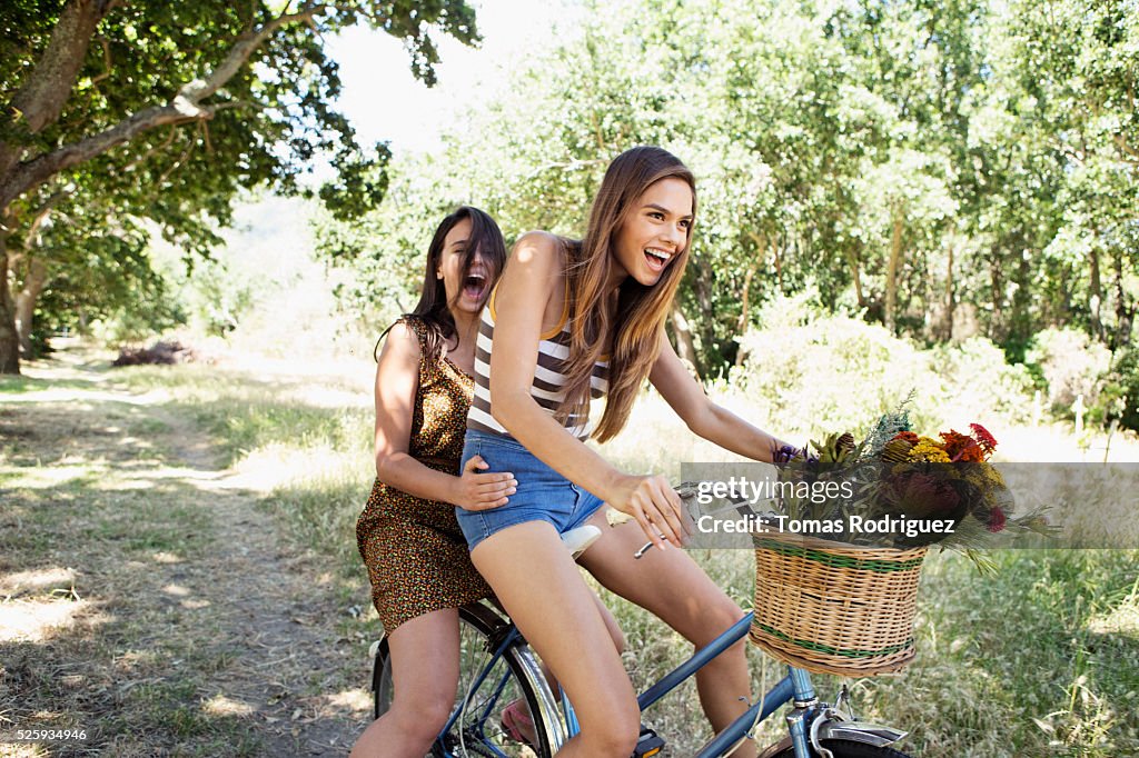 Young women riding bicycle together