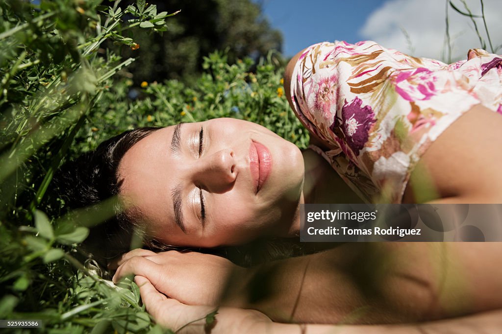 Portrait of young woman lying on grass with eyes closed