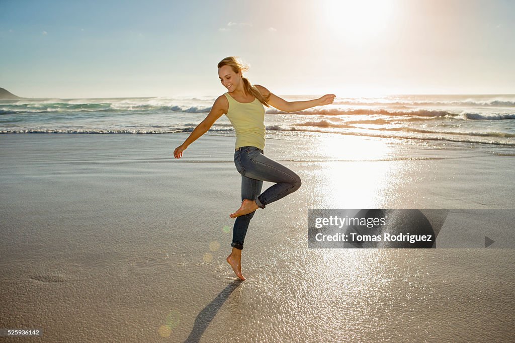 Portrait of young adult woman on beach standing on one leg