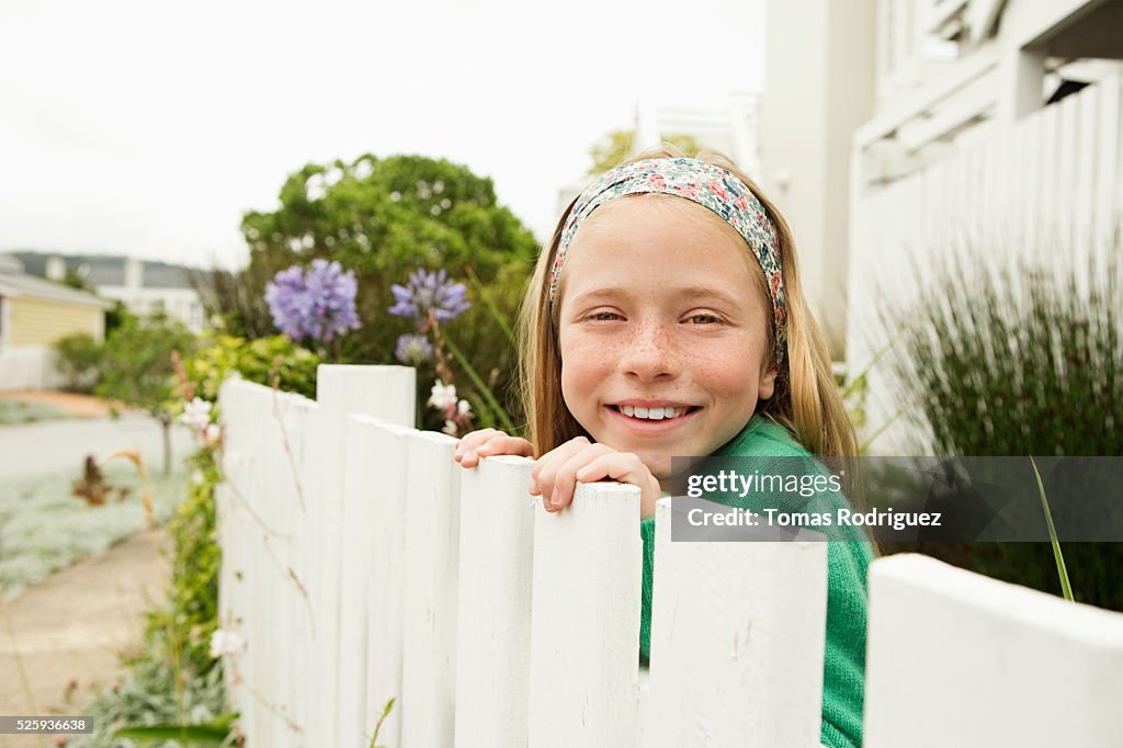 Girl(8-9) hiding behind fence