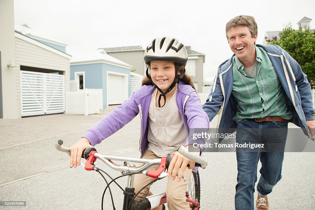 Father teaching girl (8-9) riding bicycle