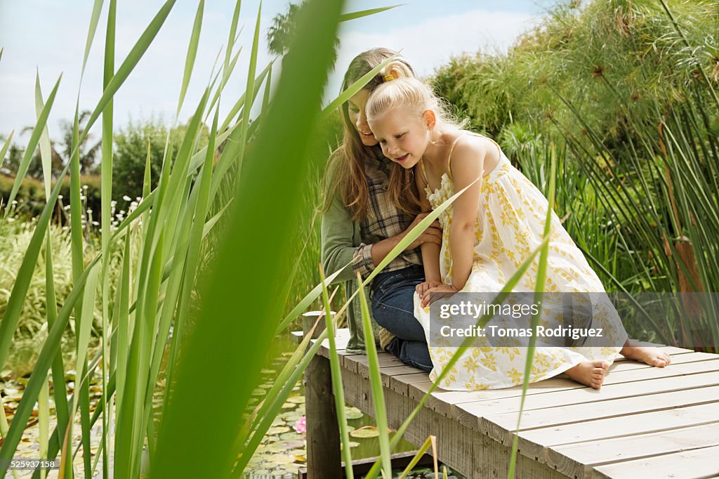 Mother and daughter (4-5) sitting on jetty