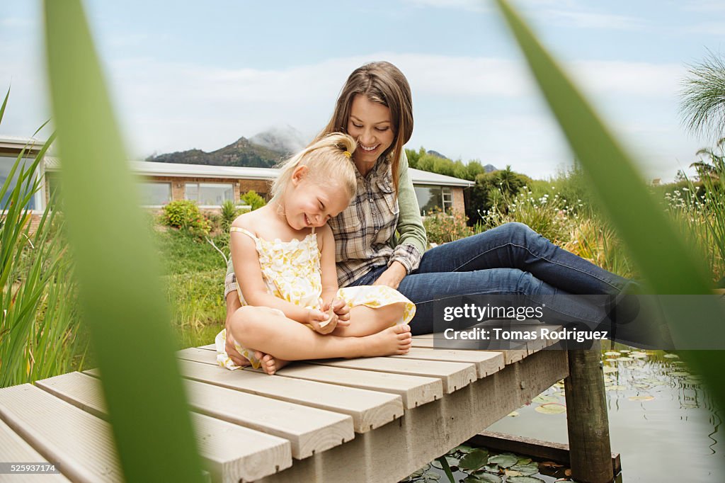 Mother and daughter (4-5) sitting on jetty