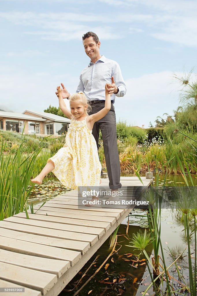 Father and daughter (4-5) dancing on jetty