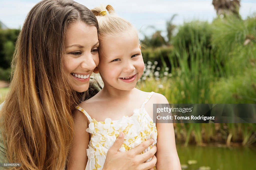 Mother embracing daughter (4-5) outdoors