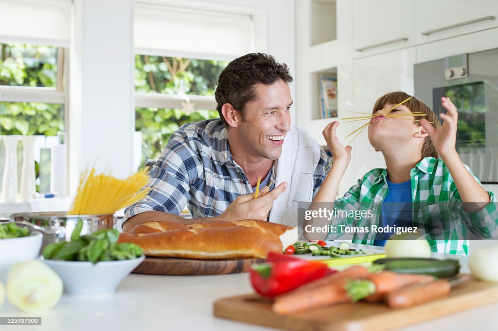 Father and son (6-7) playing in kitchen