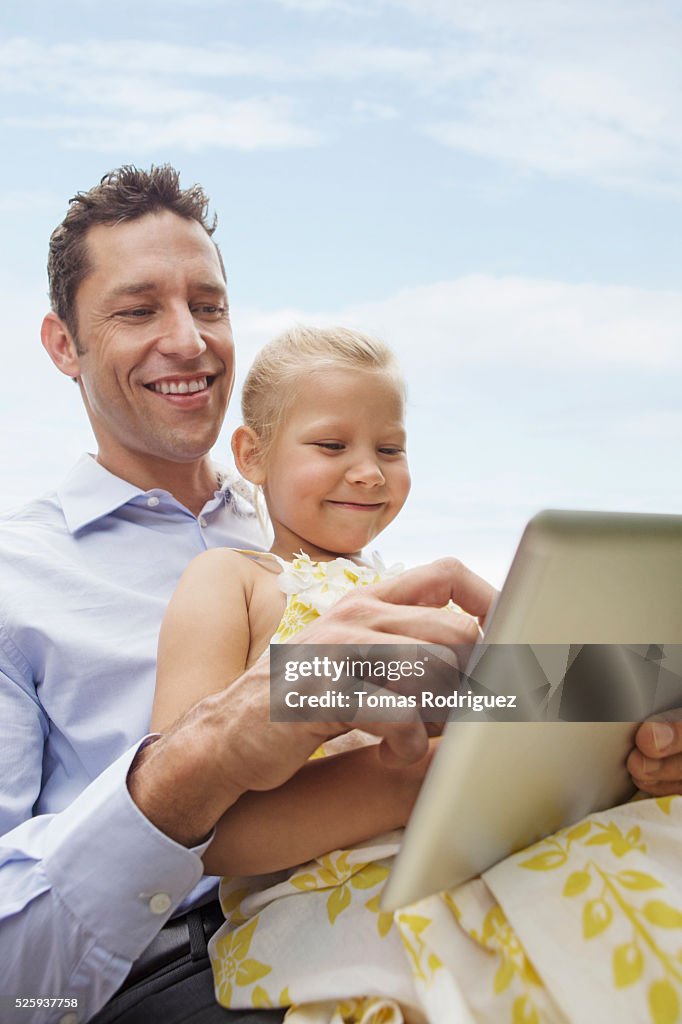 Father and daughter using digital tablet (4-5) outdoors