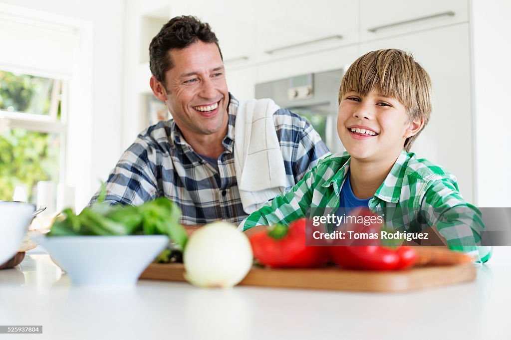 Father and son (6-7) preparing food in kitchen