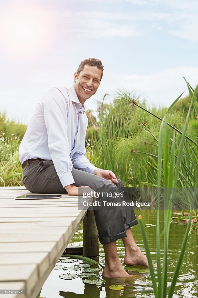 Man sitting on jetty with digital tablet