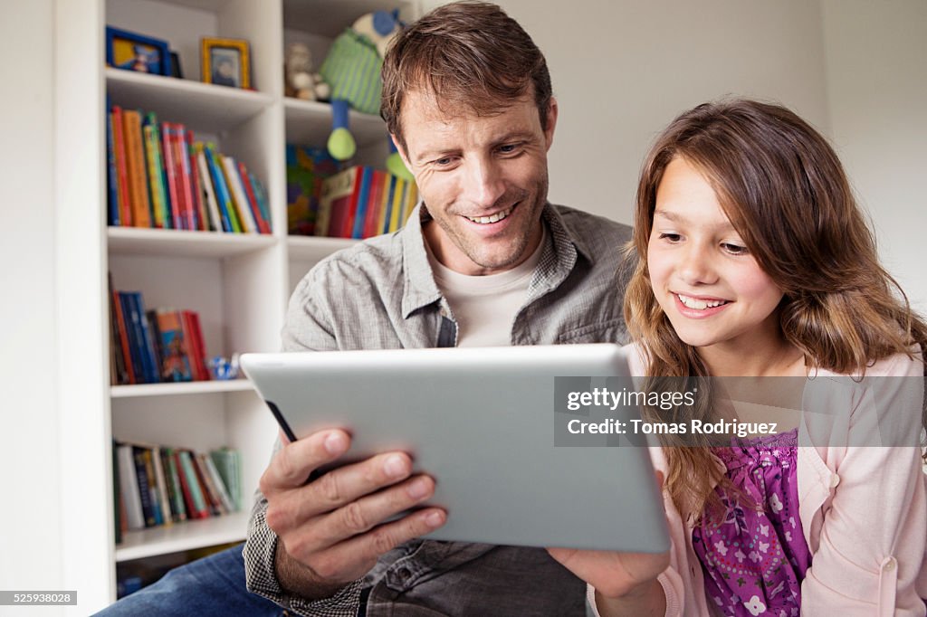 Father with daughter (8-9) using digital tablet