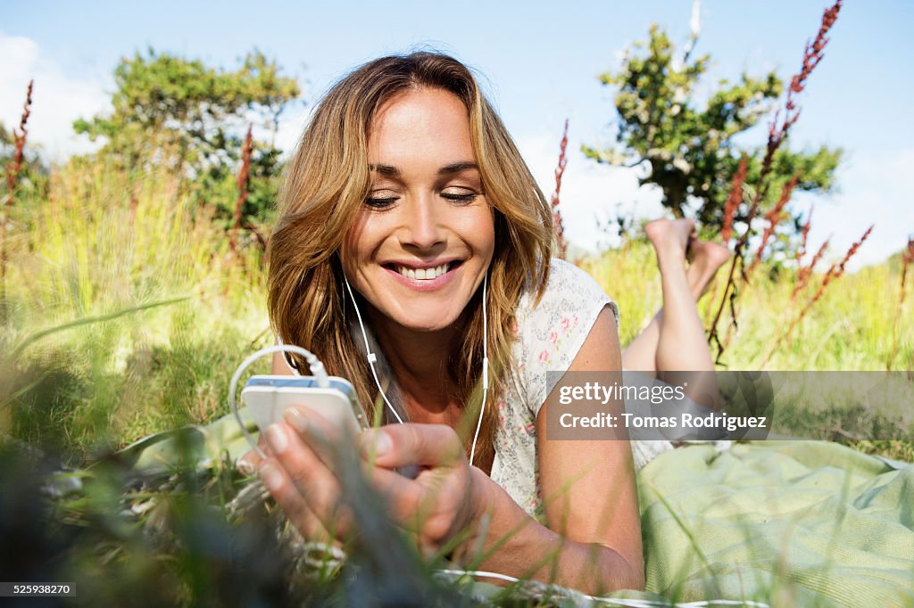 Young woman sitting among grass and using mobile phone