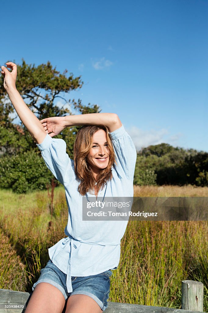 Young woman sitting on wooden fence