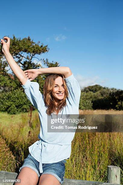 young woman sitting on wooden fence - calções imagens e fotografias de stock