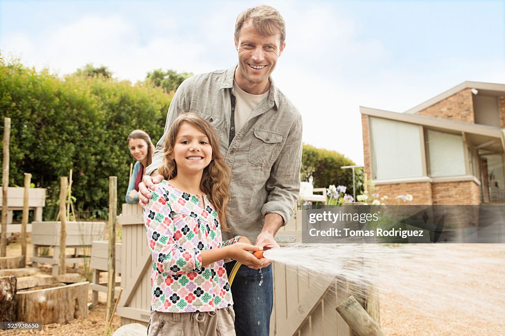 Father with daughter (8-9) watering vegetable garden