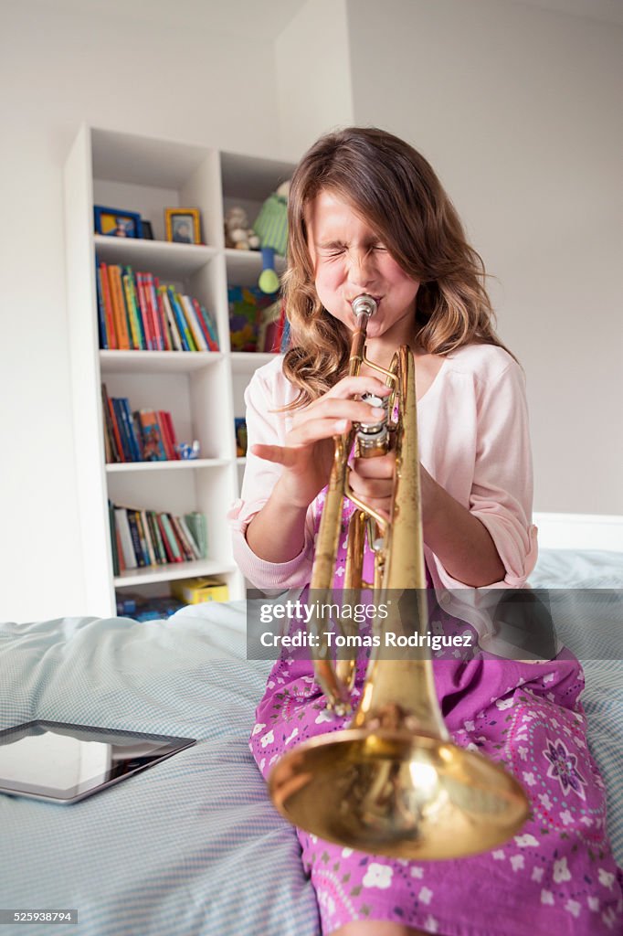 Girl (8-9) playing trumpet in bedroom