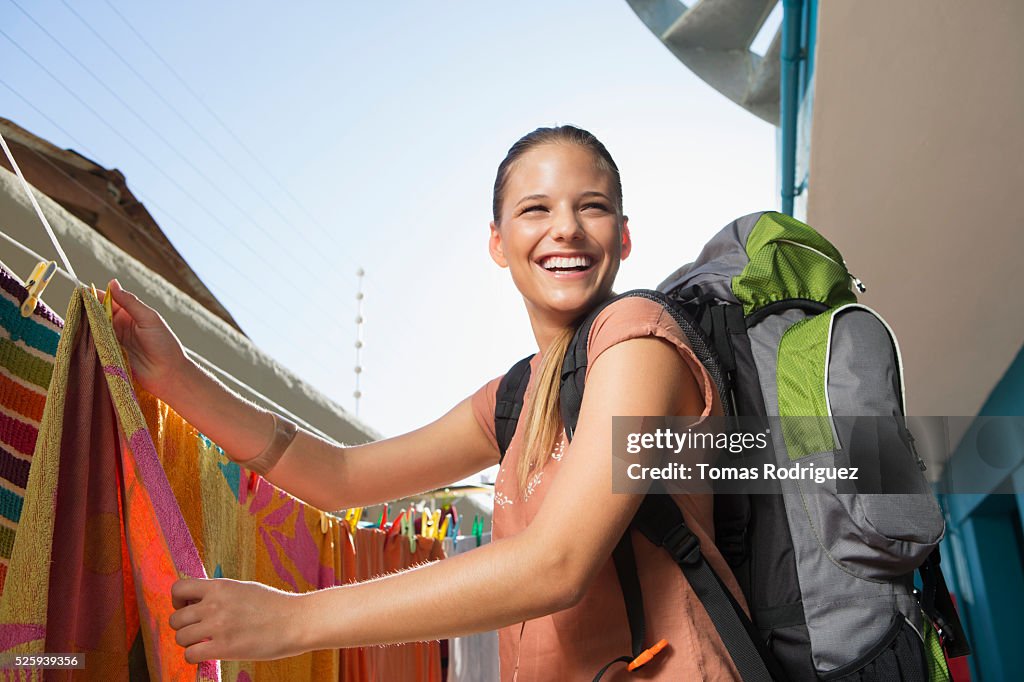 Young woman with backpack hanging laundry