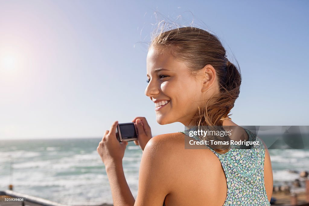 Young woman taking pictures at seaside