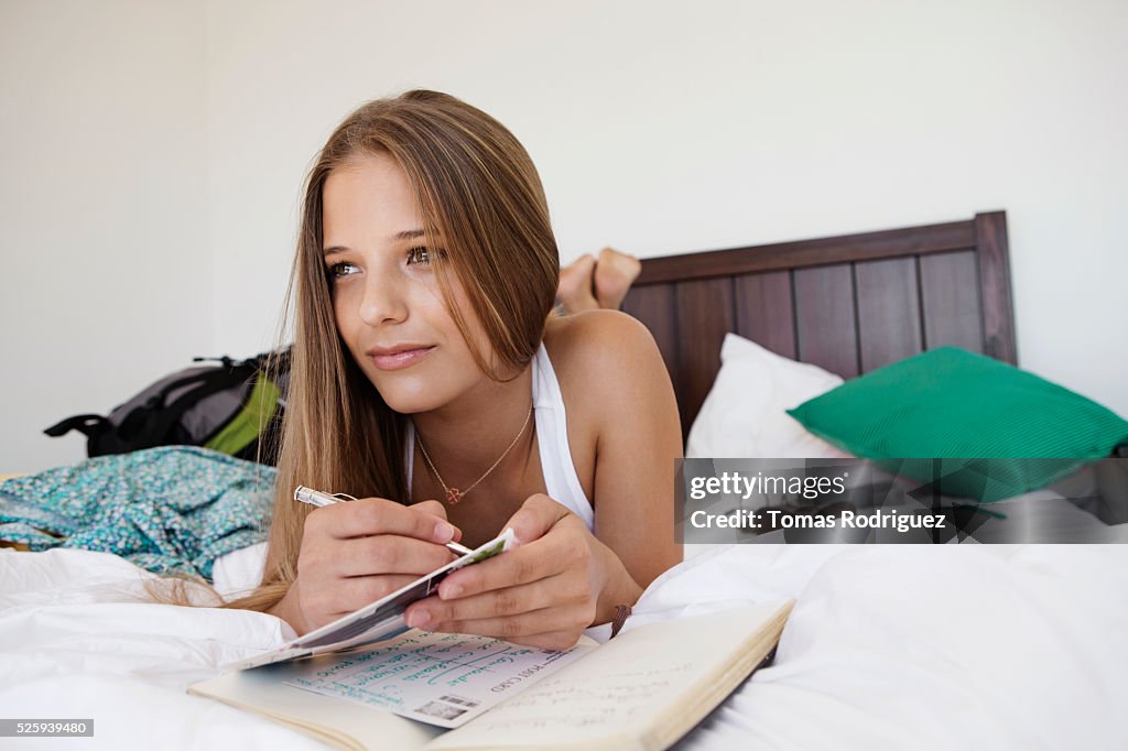 Woman lying on bed and writing postcards