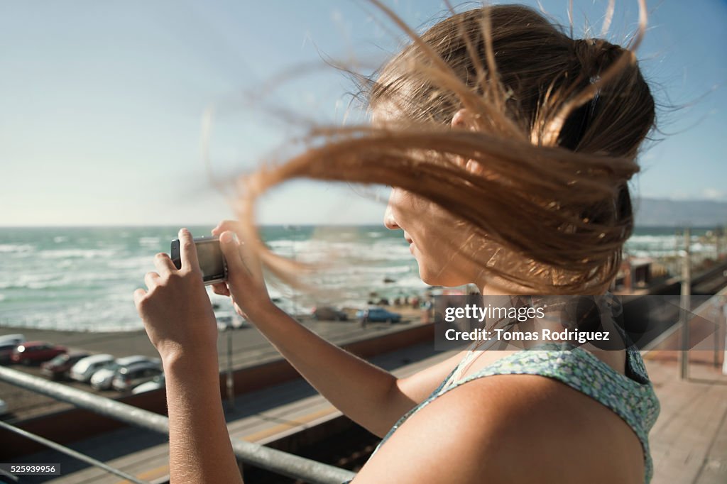 Woman standing on pier and taking picture