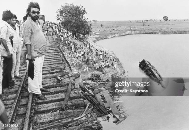 Onlookers gaze at the wreckage after a cyclone blew a crowded train off a bridge into the River Bagmati in Bihar, killing hundreds of people, June...