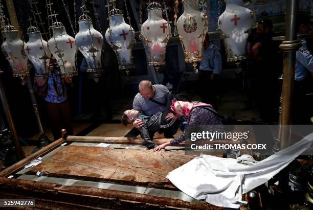 Christian Orthodox pilgrims pray with their handicapped son inside the Church of the Holy Sepulchre in Jerusalem's Old City during the Good Friday...