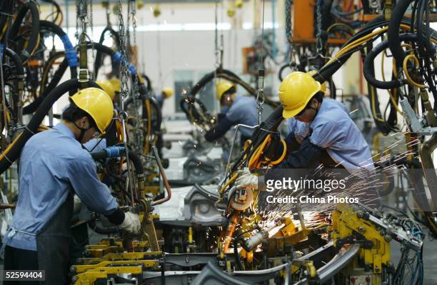 Employees on the assembly line produce cars in Mazda's "Family" line of vehicles at China First Automobile Works Group Haima Automobile Co., Ltd....