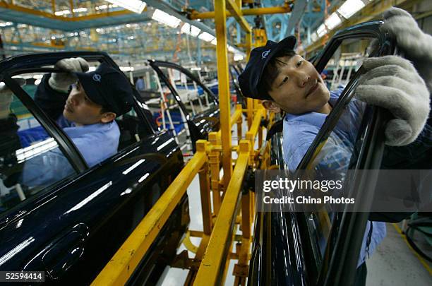 Employees work on doors for Mazda's "Family" line of vehicles at China First Automobile Works Group Haima Automobile Co., Ltd. April 6, 2005 in...