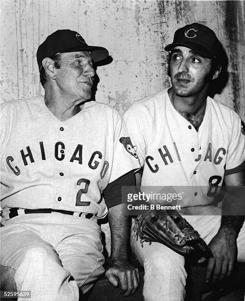 American baseball player and manager Leo Durocher of the Chicago Cubs sits on the bench in the visitors' dugout and talks with new Cubs player Joe...