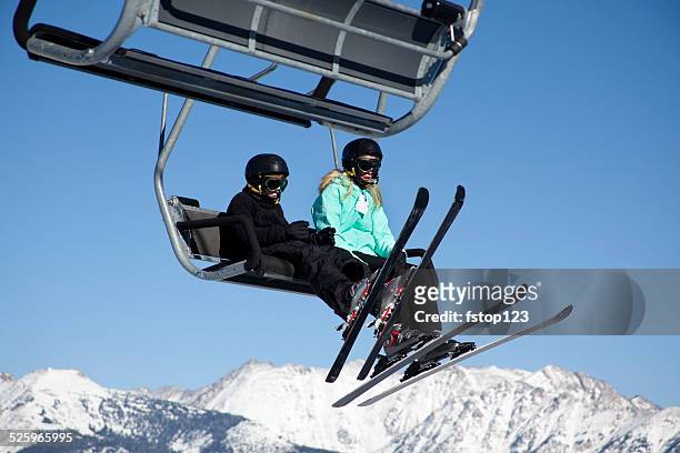 two skiers ride ski lift to top of mountain. sky. - woman on ski lift stock pictures, royalty-free photos & images