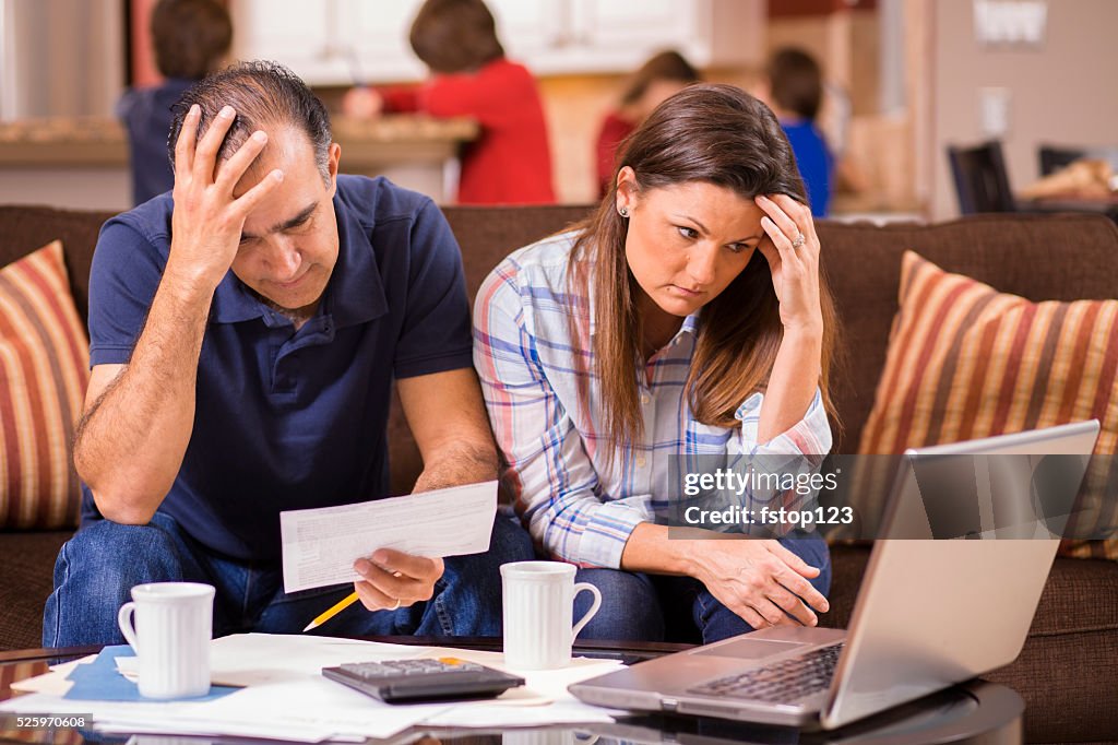 Latin descent couple paying monthly bills at home.  Frustration.