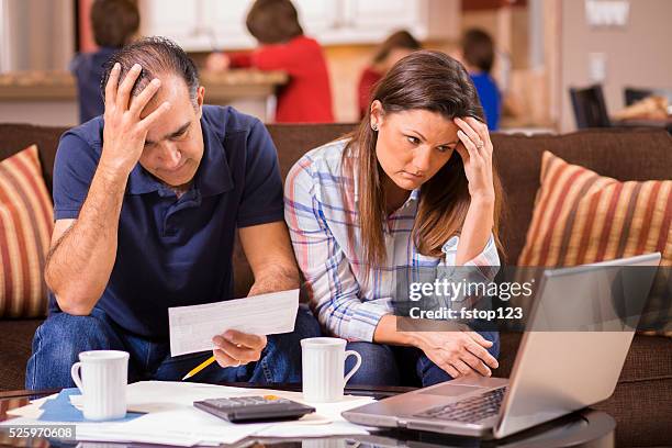 latin descent couple paying monthly bills at home.  frustration. - mortgage document stock pictures, royalty-free photos & images