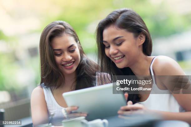 two young women using a tablet computer - filipino girl stockfoto's en -beelden