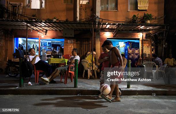Young boy and his friend plays football in the streets of Favela Rocinha, the biggest Favela in South America in Rio de Janeiro outside a bar.