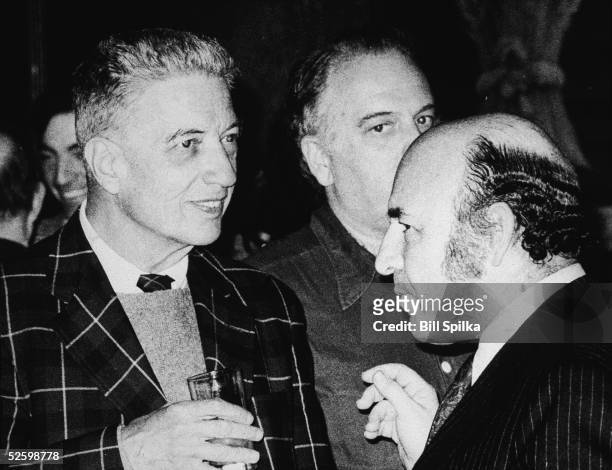 American record producer, musician, and music critic John Hammond holds a glass and talks to jazz impresario George Wein at a party, 1970s.