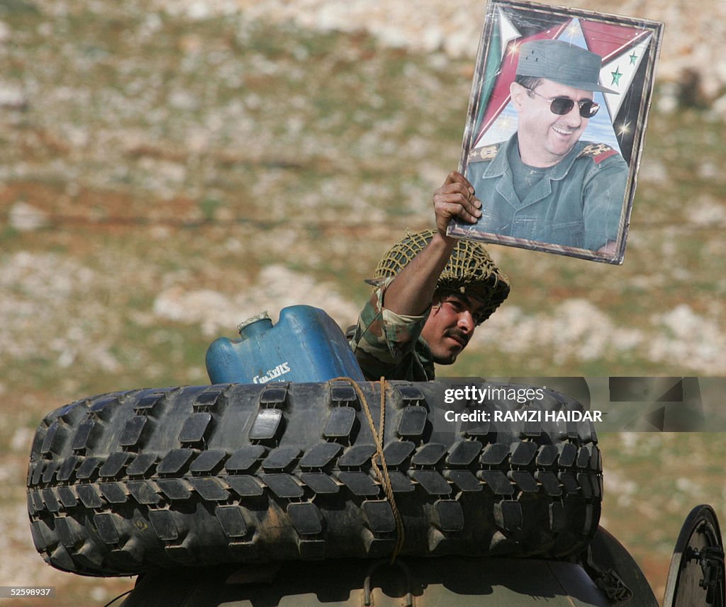 A Syrian soldier waves a poster of his P