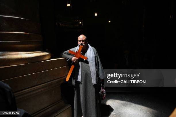 Coptic Orthodox Christian pilgrim from Egypt holds a wooden cross at the Church of the Holy Sepulchre during the Good Friday procession in...