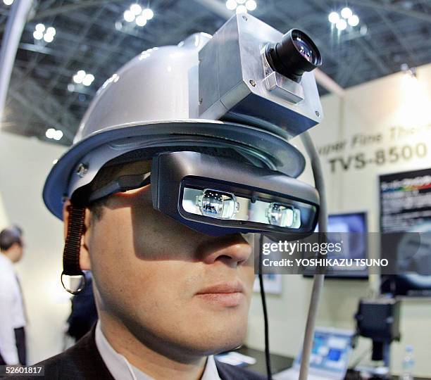 Japan's electronics venture Nippon Avionics employee Hiroki Shibata displays the prototype model of head-mount-display infra-red helmet which enables...