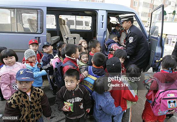 Policeman helps schoolchildren into a minibus, 08 April 2005 in Shenyang, in northeast China's Liaoning province. The popular form of transport for...