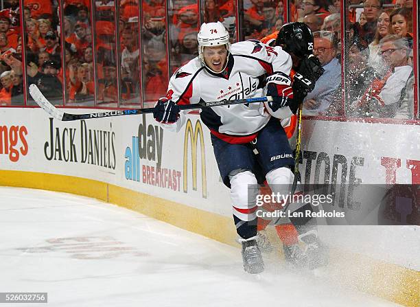 John Carlson of the Washington Capitals checks Ryan White of the Philadelphia Flyers into the boards in Game Four of the Eastern Conference First...